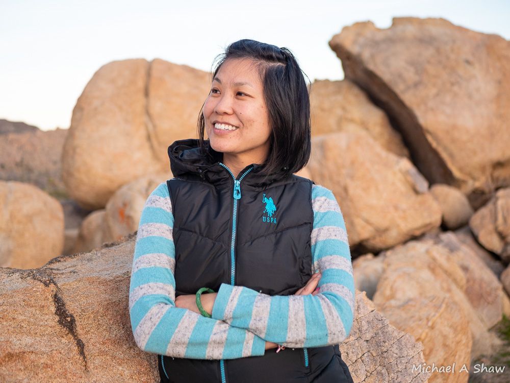 Carrie Leung looking off to the side and smiling among large boulders