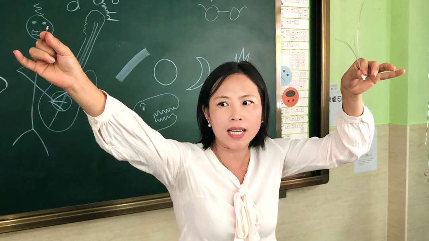 Linda Jie Ming teaching at a chalkboard