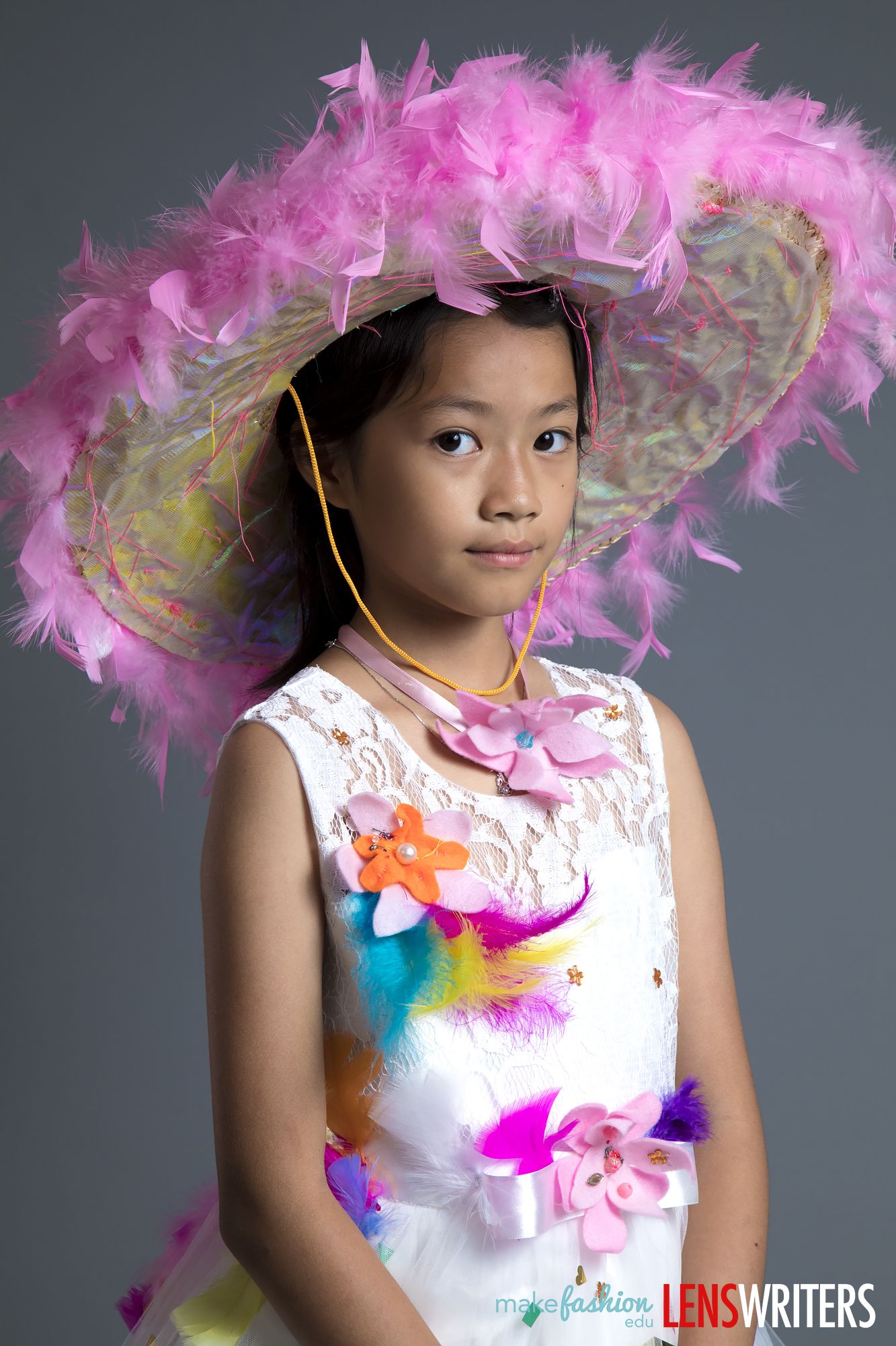 Student wearing a wide feathered hat and floral quinceañera dress
