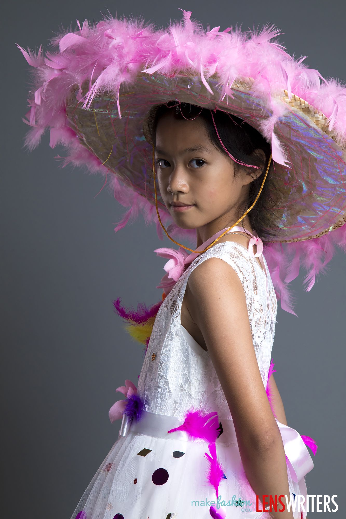 Side profile of a student wearing a wide feathered hat and lace dress