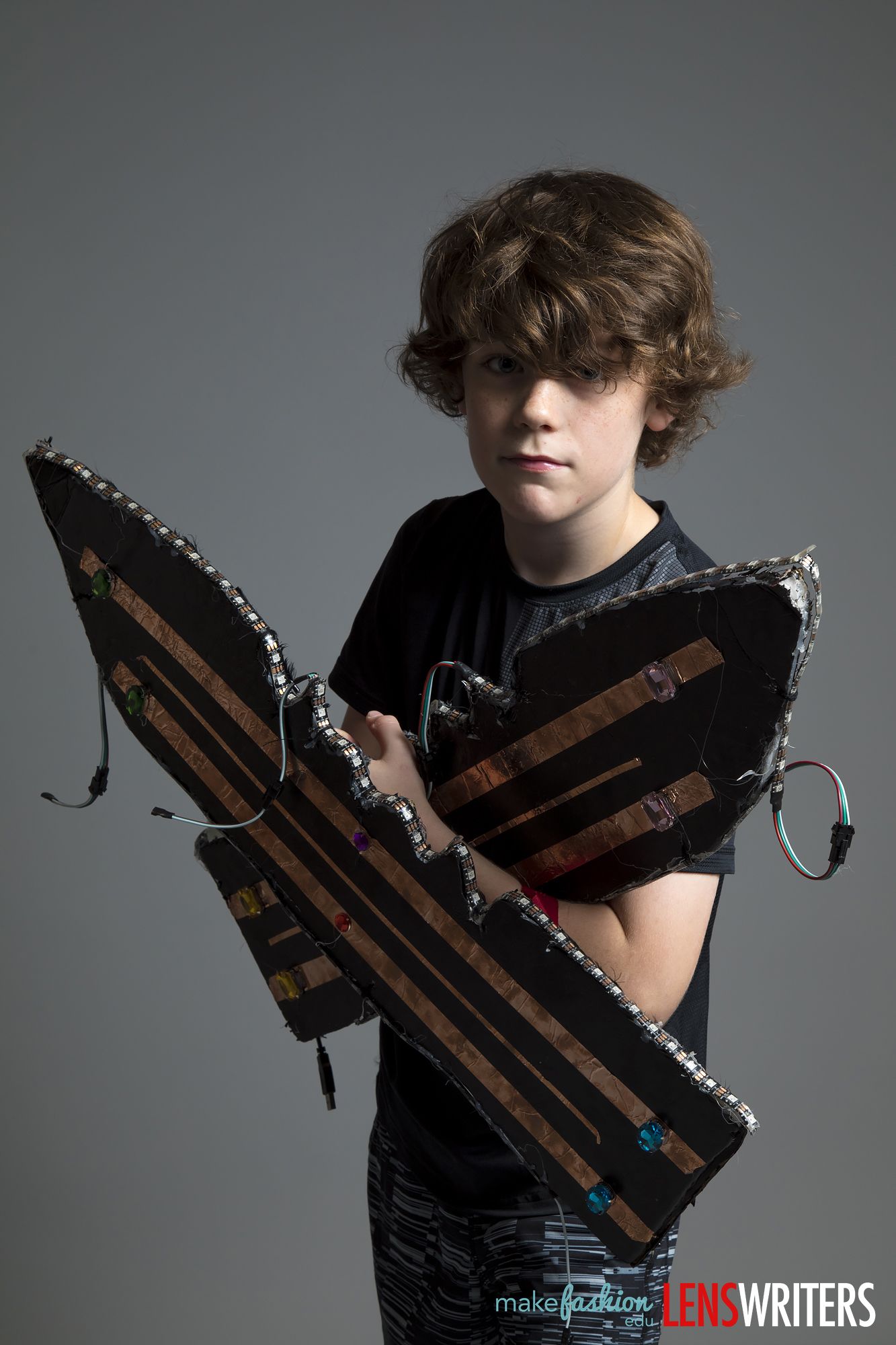 Student stands holding a spiked LED wing piece across his chest