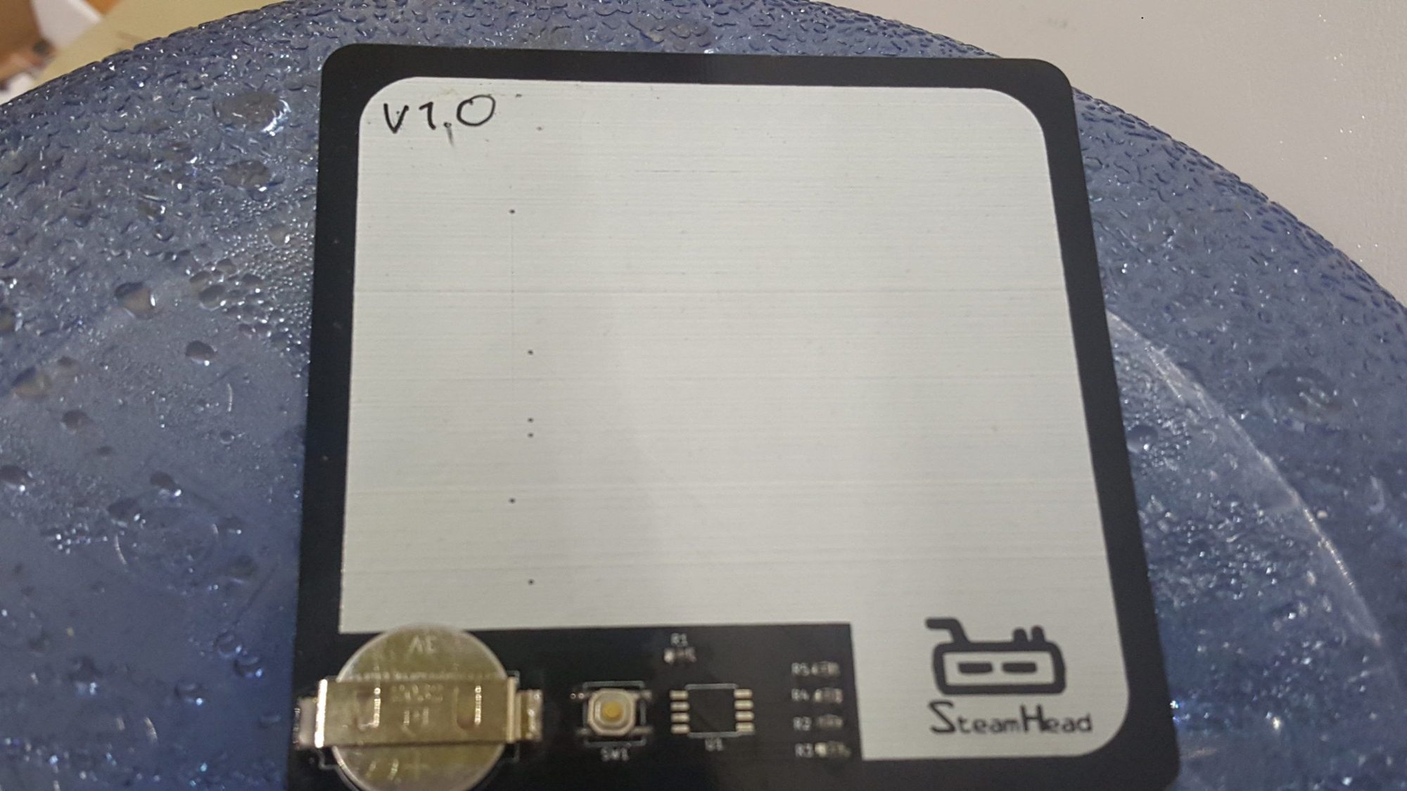 Blank PCB postcard prototype labeled V1.0 with coin battery