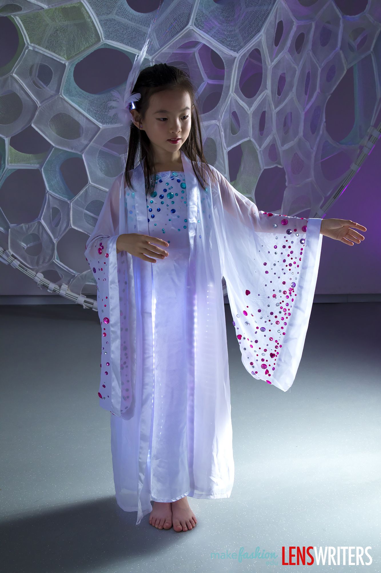 Student walking in a glowing white dress with illuminated hem