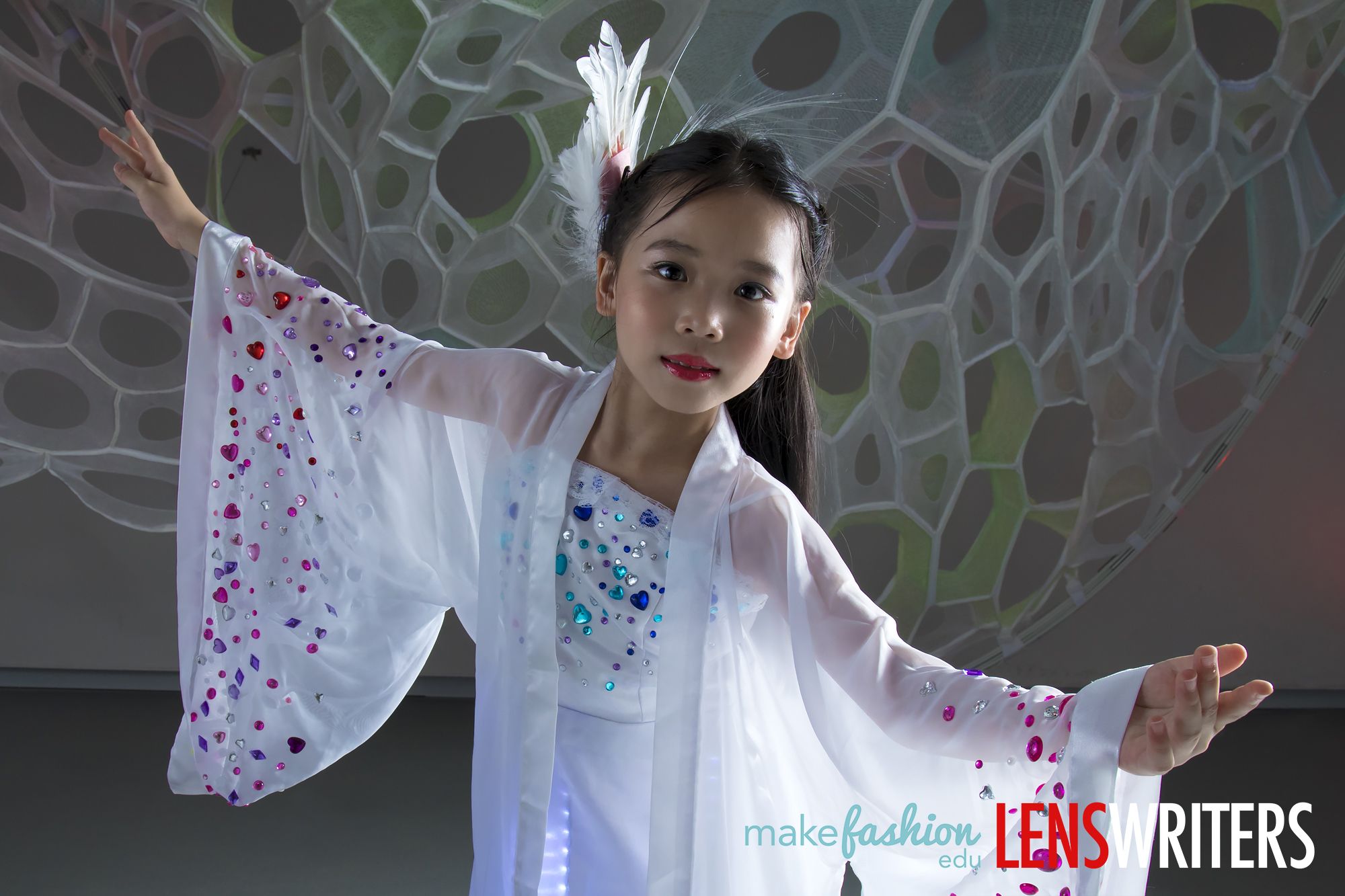 Young designer in a glowing white LED gown with feather headpiece