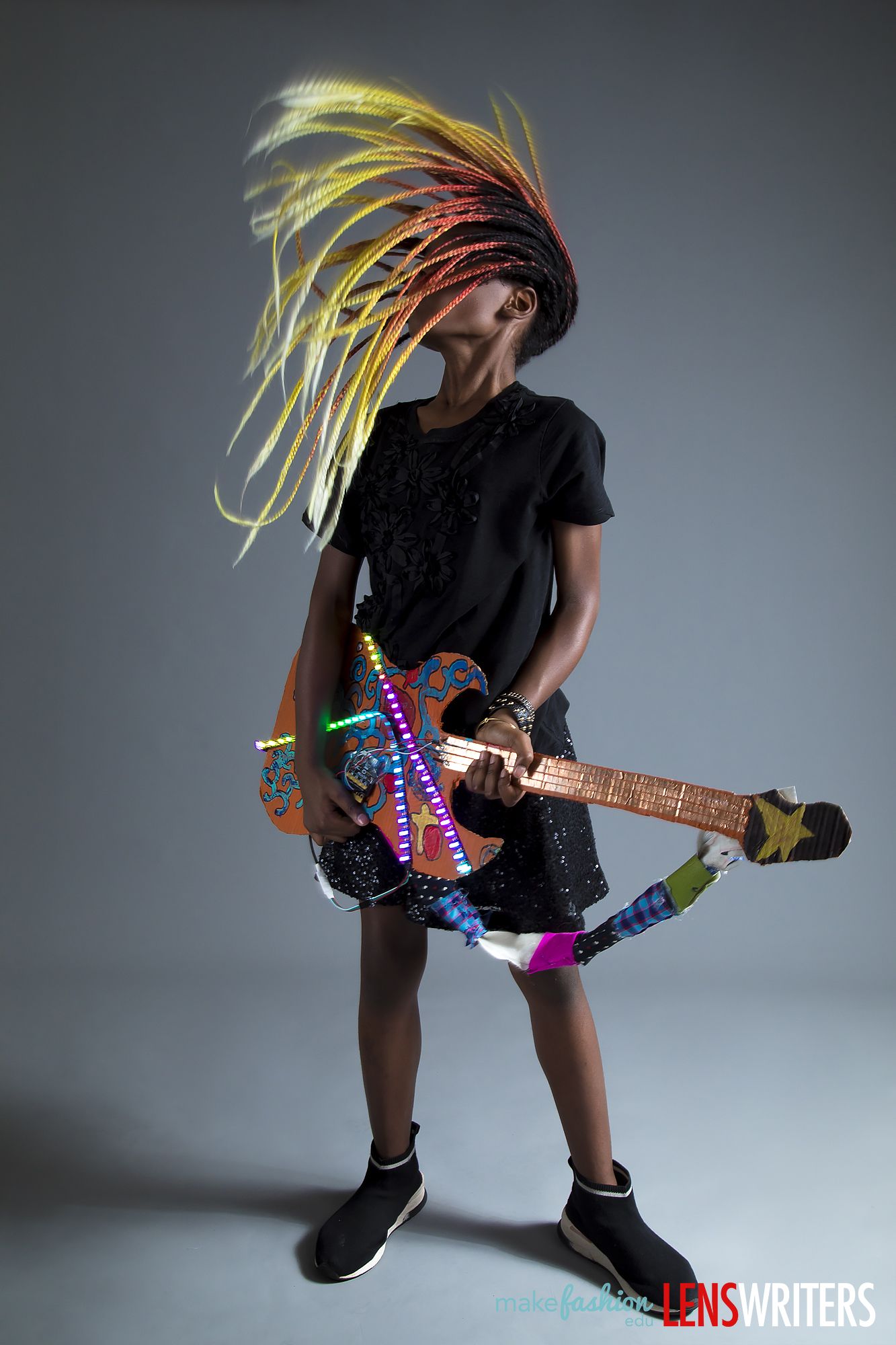 Student headbanging while playing the LED-lit cardboard guitar