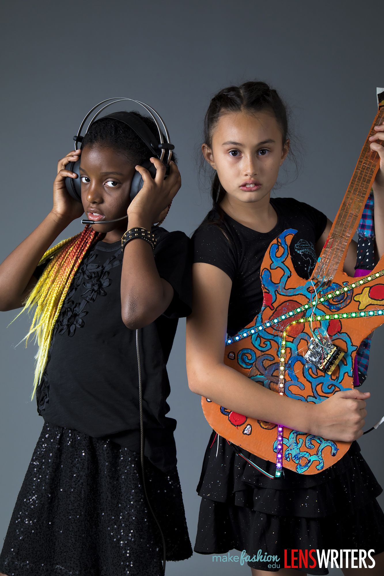 Two students standing back to back with the illuminated guitar
