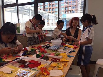 Anina Net helping students sort colorful fabric scraps at a workshop table