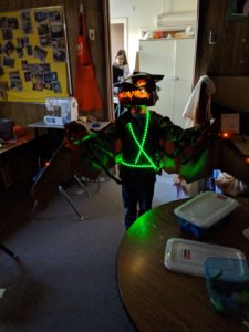 A student wearing a glowing green LED costume in a doorway