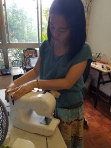 Olivia sewing fabric on a machine near a window
