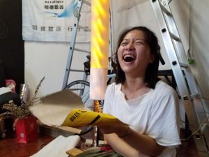 Olivia laughing while holding up a glowing lamp shade she made