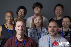 Group of seven people posing together at a conference, wearing event lanyards
