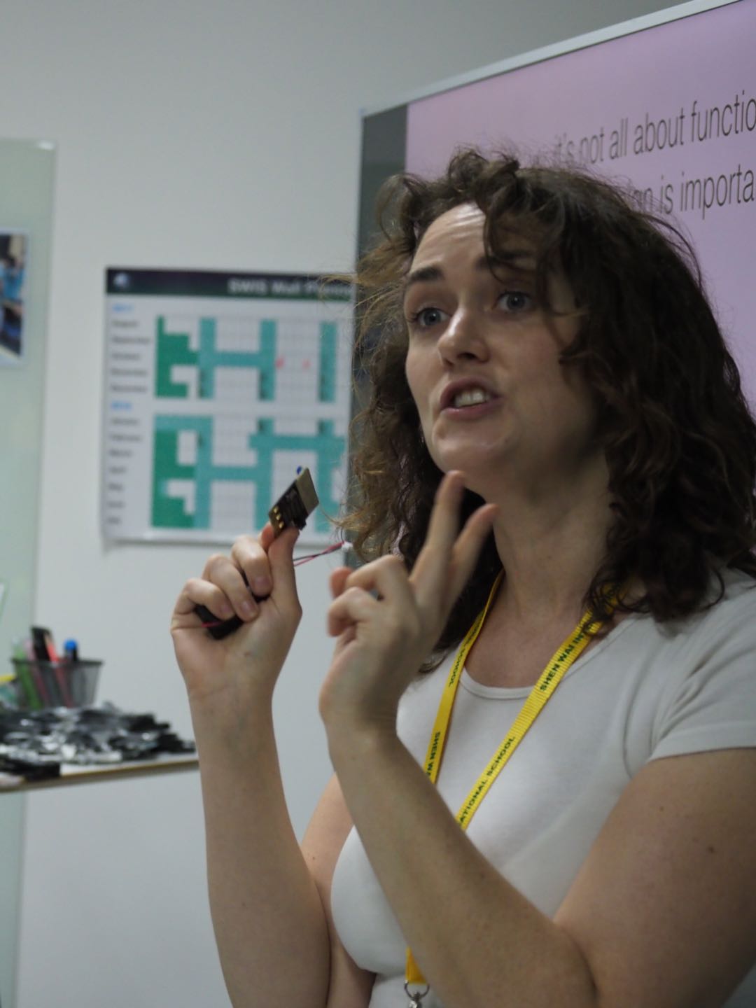 Helen holding an electronic component while presenting to a group