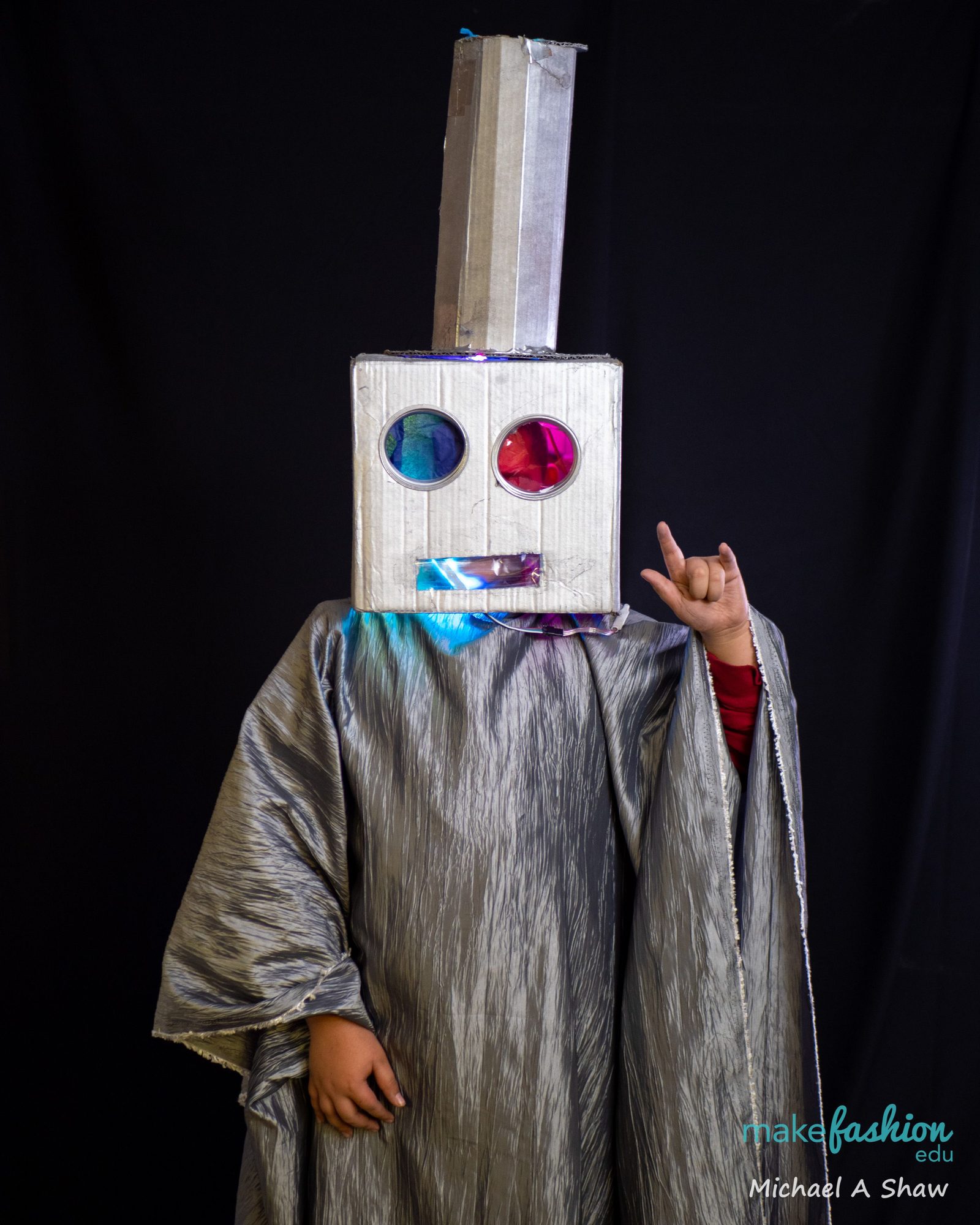 A student in a light-up robot head costume making a rock-on gesture