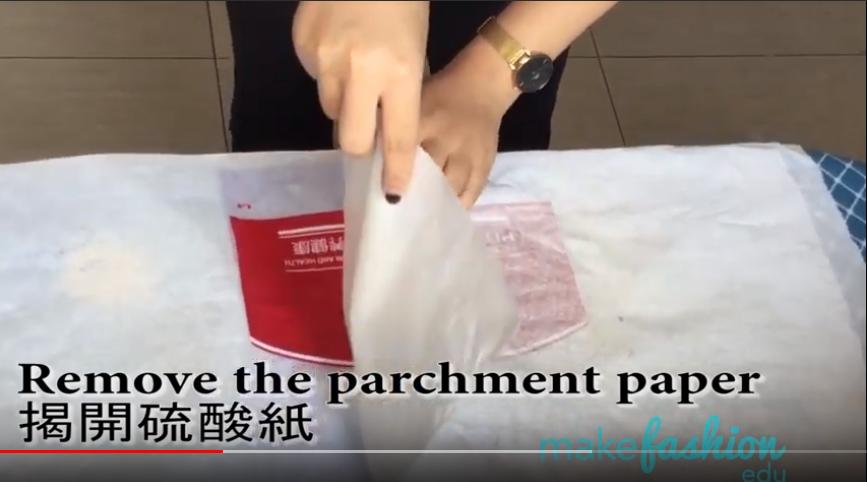 Video still of hands peeling parchment paper off fused plastic bag fabric