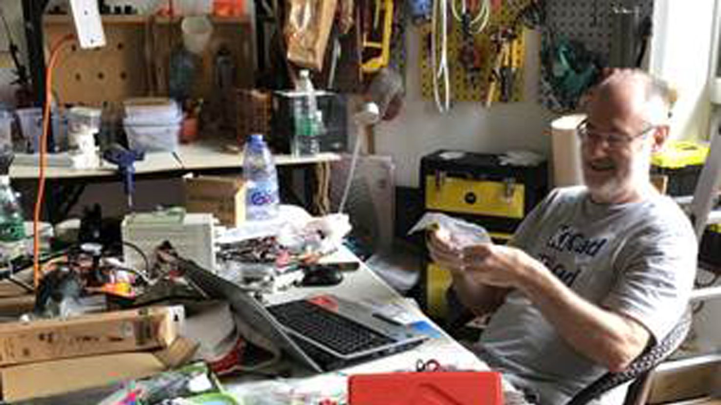 Paul working at a cluttered workbench in the SteamHead workshop