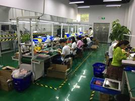 Factory workers assembling electronics at benches on M5's production floor