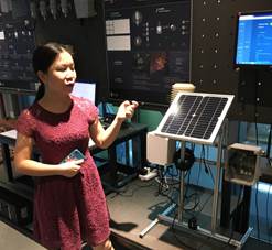 Woman presenting a solar-powered tea farm monitoring station display
