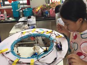 A student assembles a wire-and-LED hoop frame in a classroom