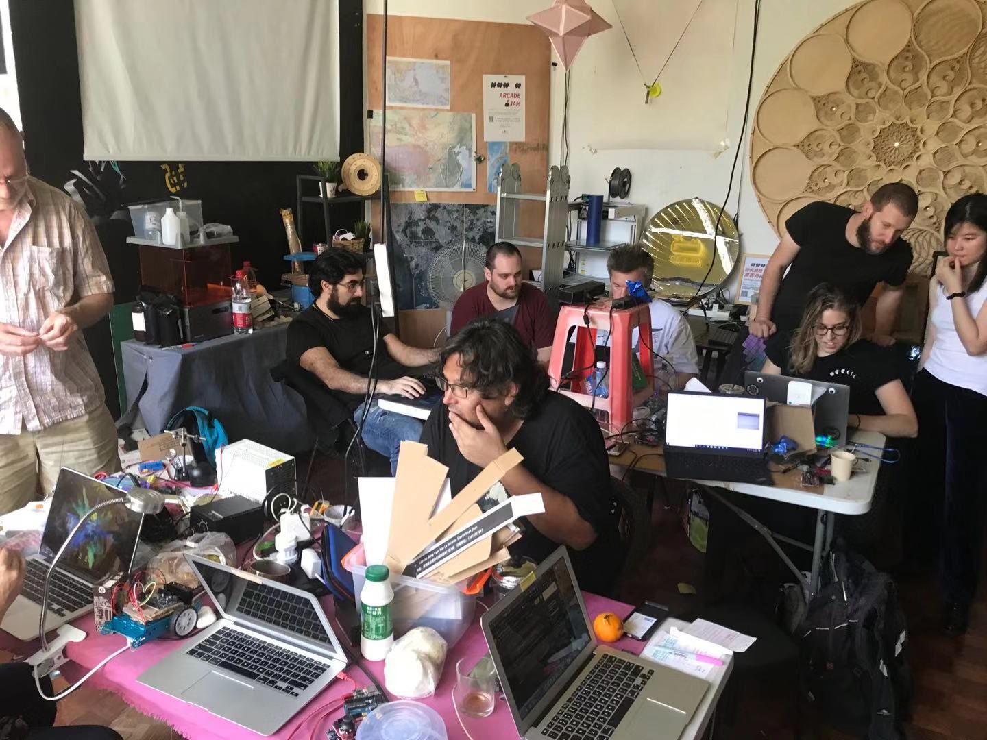 Makers working at laptop-covered tables during the arcade jam