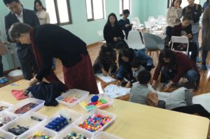 Students decorating tee shirts with craft supplies at a table