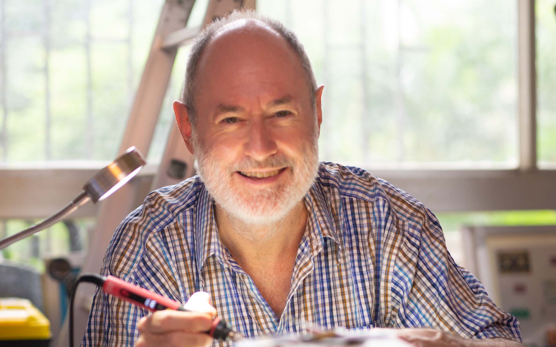 Paul Hamilton smiling while holding a soldering iron