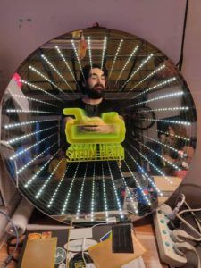 Infinity mirror reflecting a face and a toy hamburger