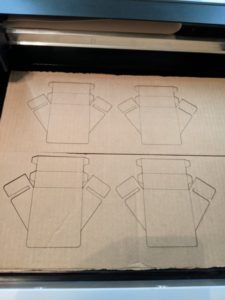 Reflector template shapes cut into cardboard on a laser cutter bed