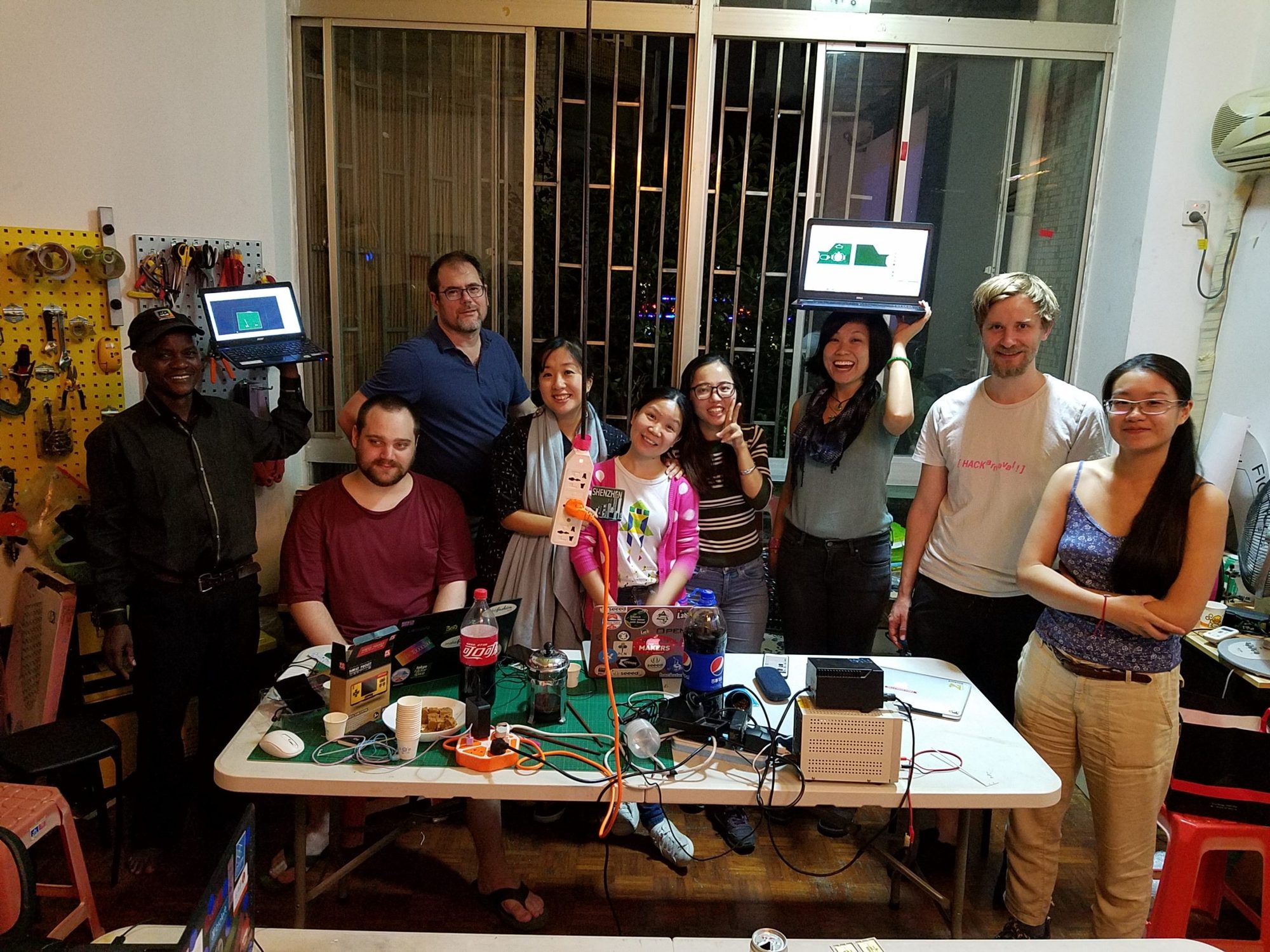 SteamHead community group photo around a project table at an evening meetup