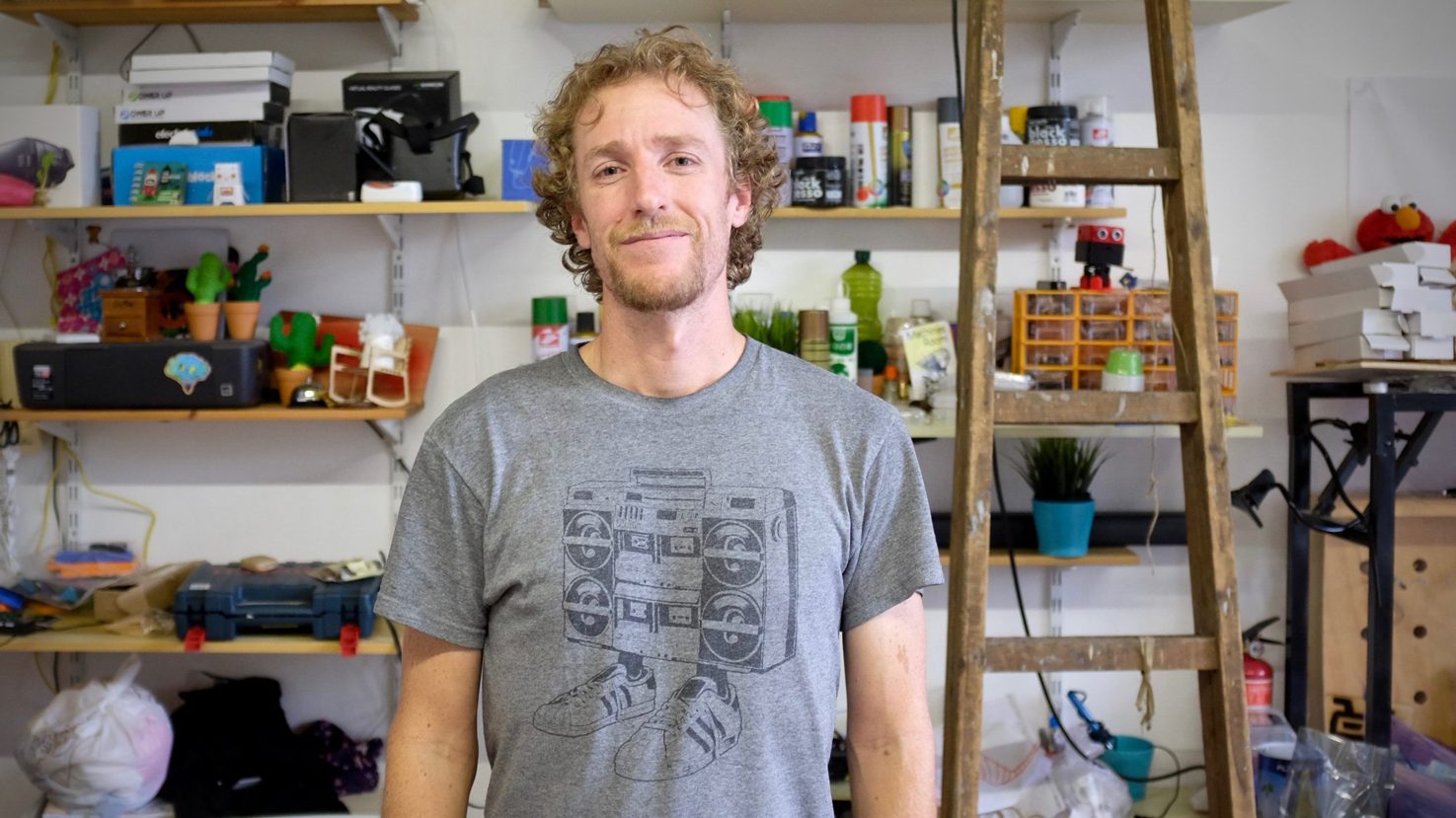 James Simpson in a workshop with shelves of equipment