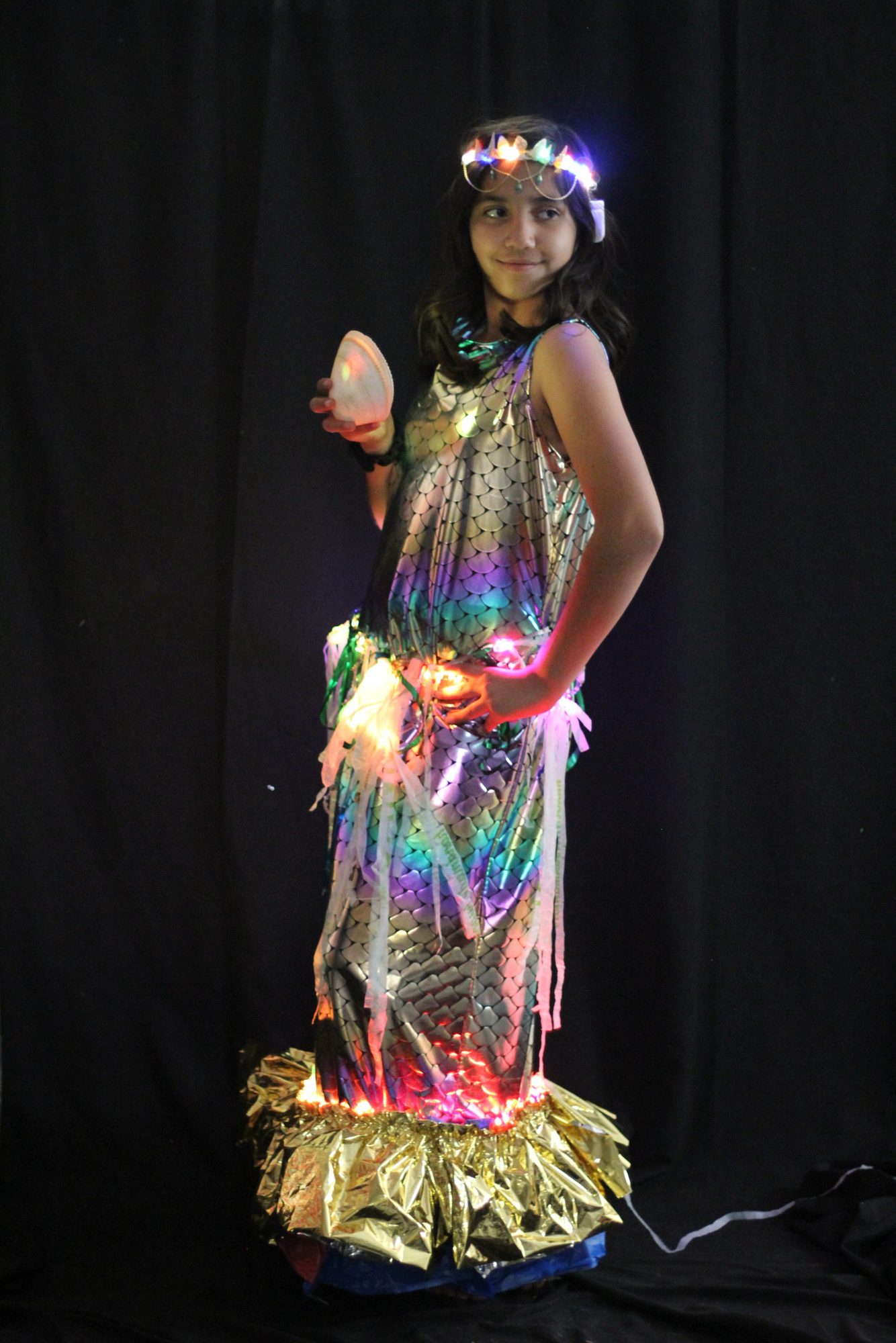Student in a light-up mermaid-scale gown holding a glowing shell