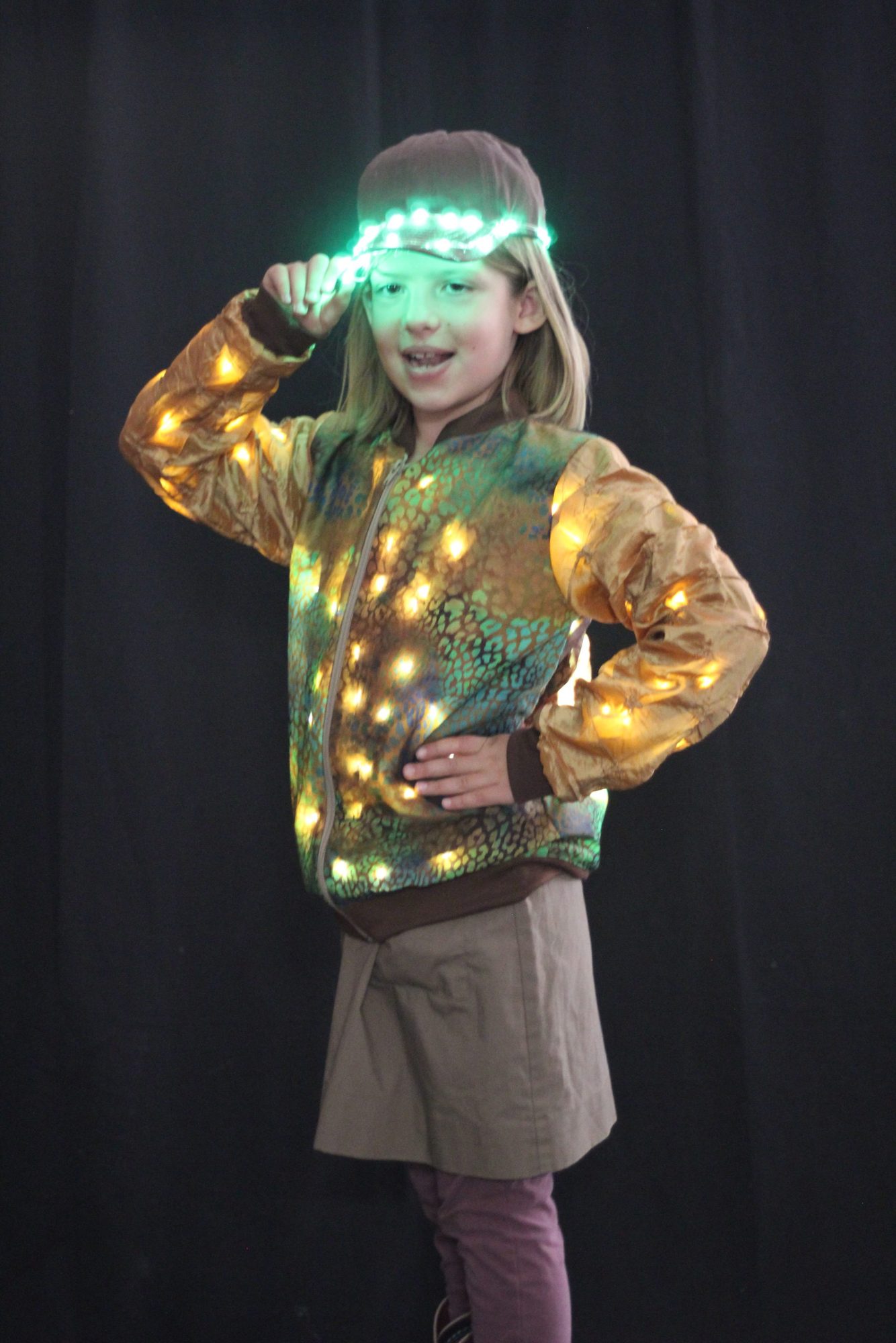Student wearing an illuminated gold jacket and light-up LED cap