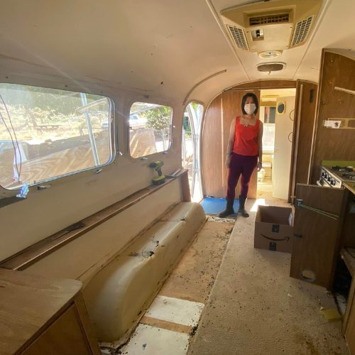 Mobile Makerspace chapter 3: a masked volunteer standing inside the stripped Airstream interior