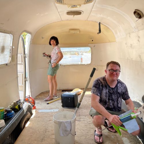 Mobile Makerspace chapter 8: two volunteers smiling inside the gutted, cream-colored Airstream interior