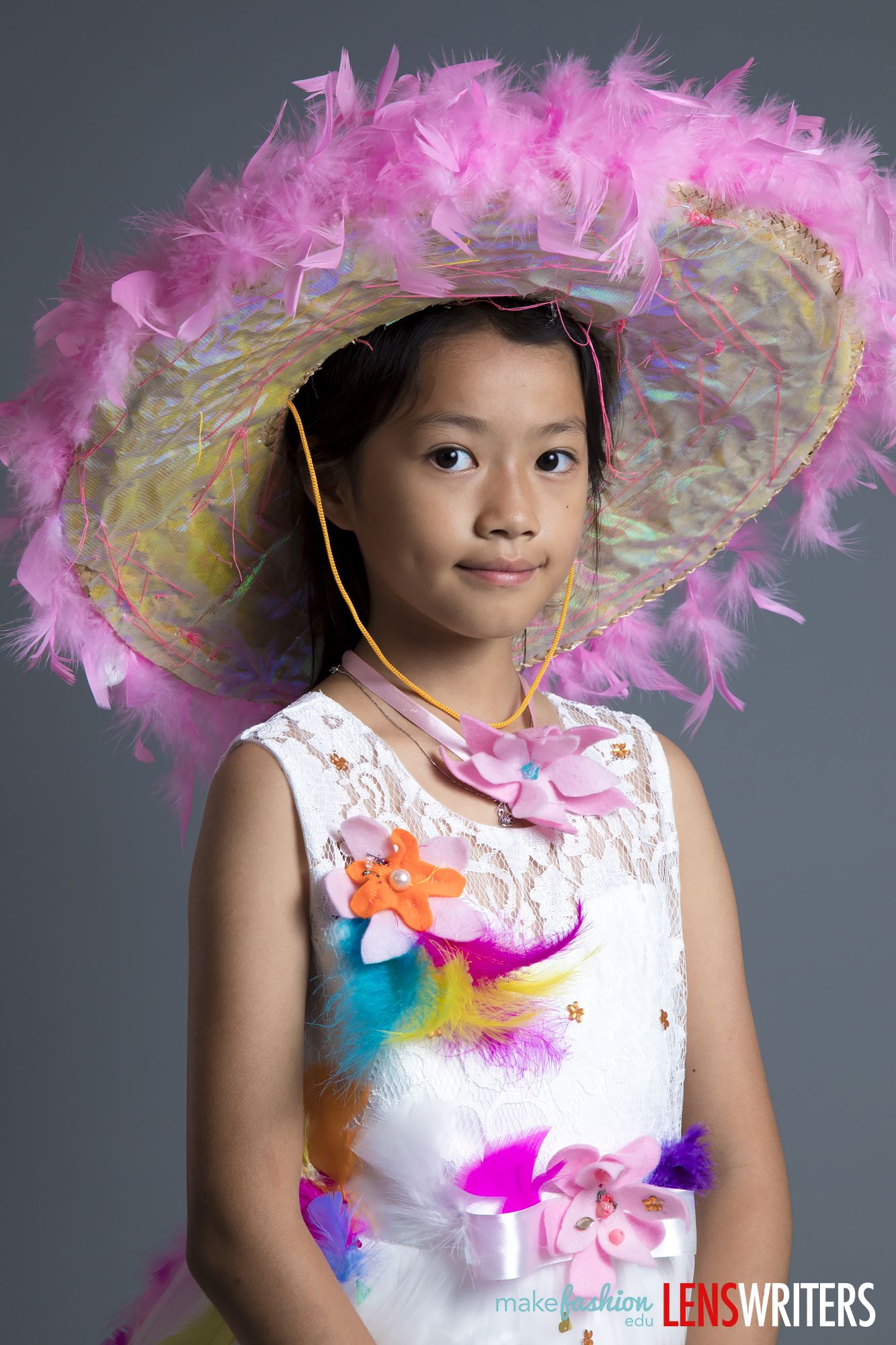 Student model in wide-brimmed pink feather hat with felt flowers on white dress