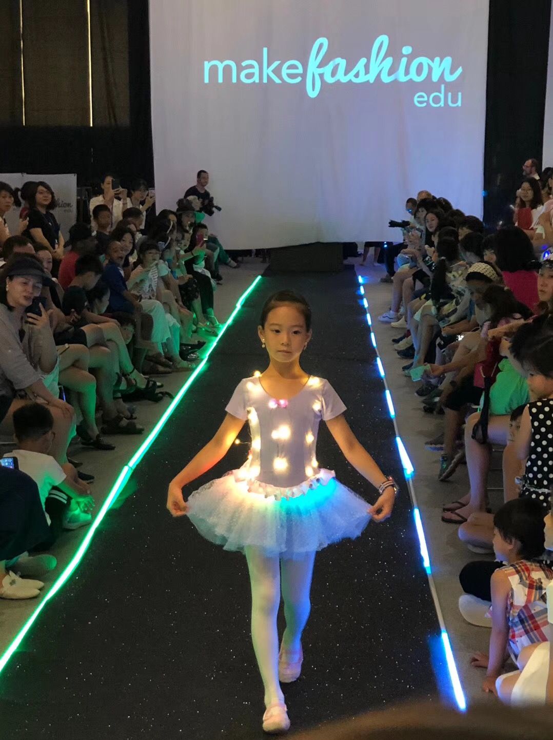 Student in an illuminated dress walking the MakeFashion Edu runway