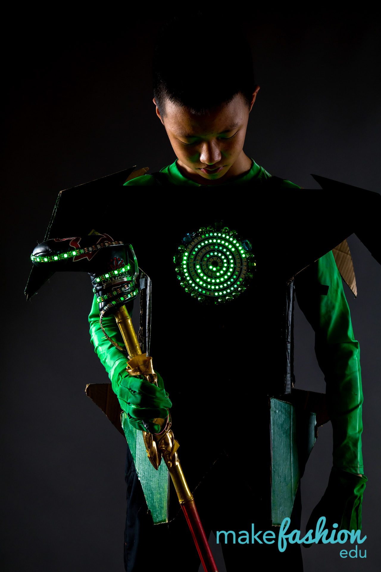 Student model in black armor with glowing green concentric-circle medallion and green LED sleeve