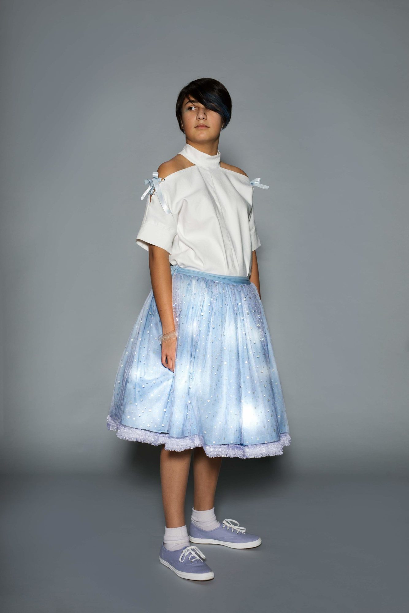 Student model in white cold-shoulder shirt and pale blue tulle skirt fully embedded with white LED lights