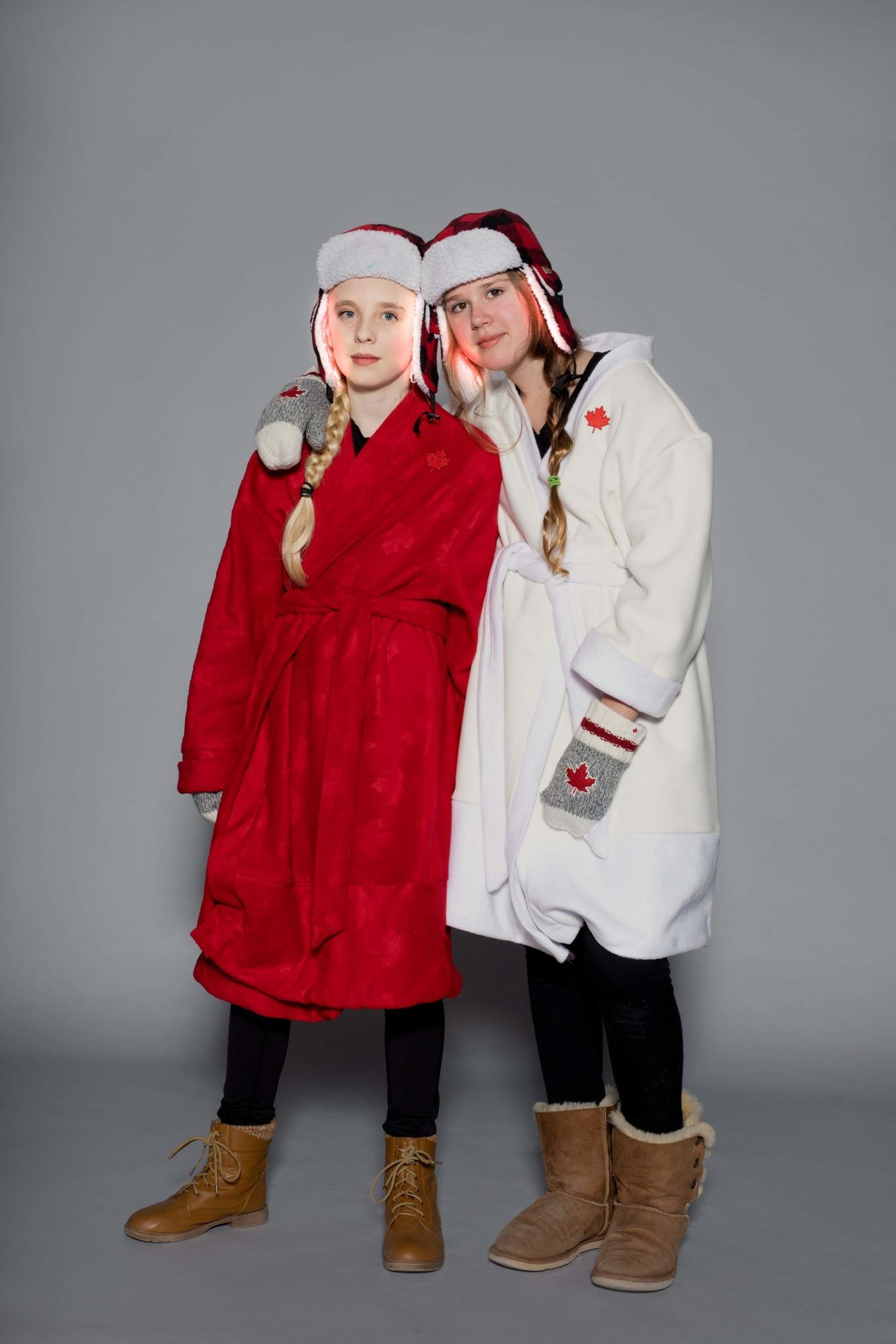 Two student models in red and white Canadian-themed outfits with LED-embellished hats and maple leaf details