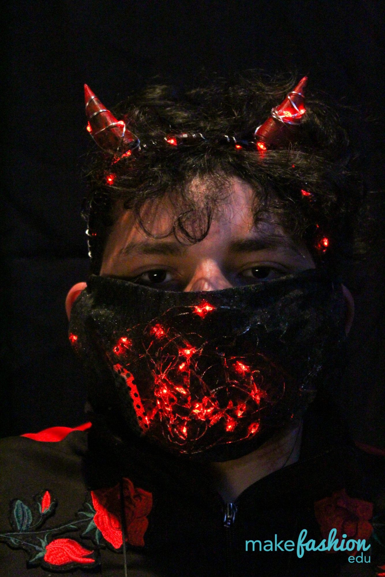 Close-up of glowing red devil horns and a lit mesh face mask