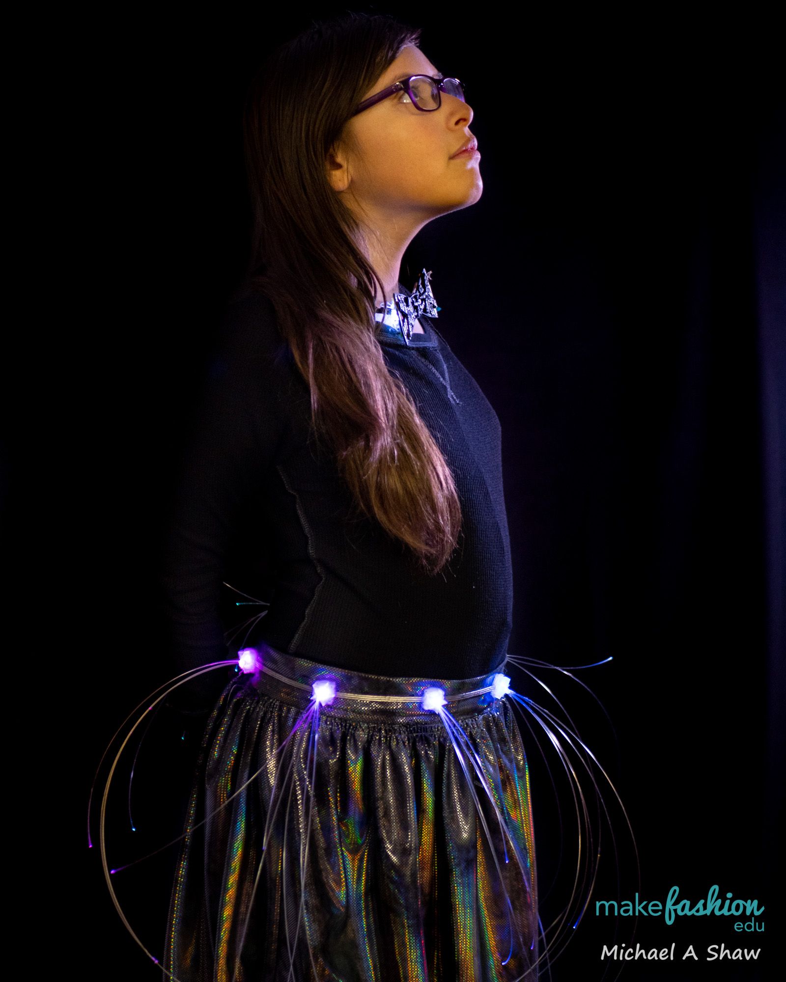 Two student models in cream garments decorated with illustrated fabric patches and lights