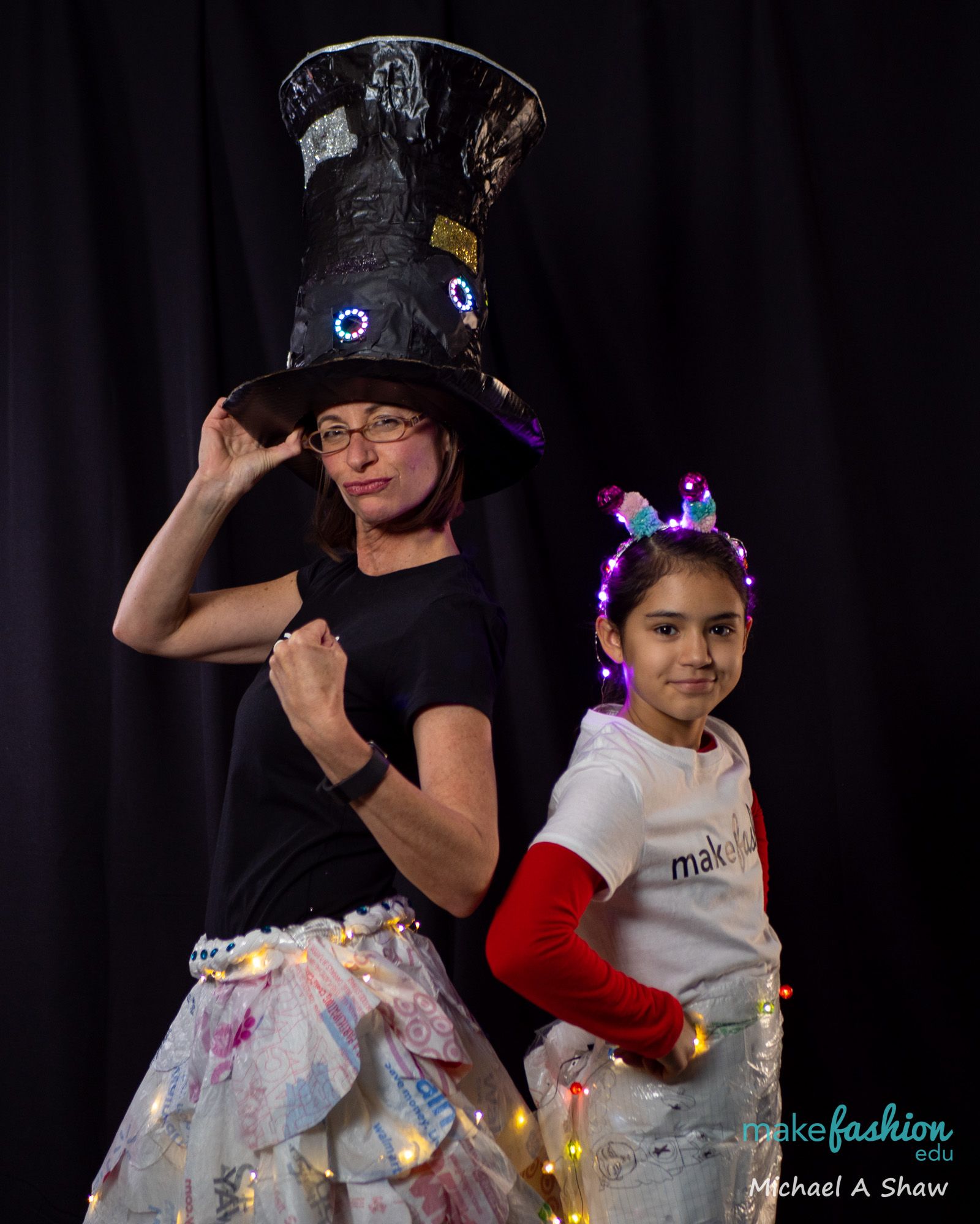 Adult and student in cream garments with glowing paper flowers