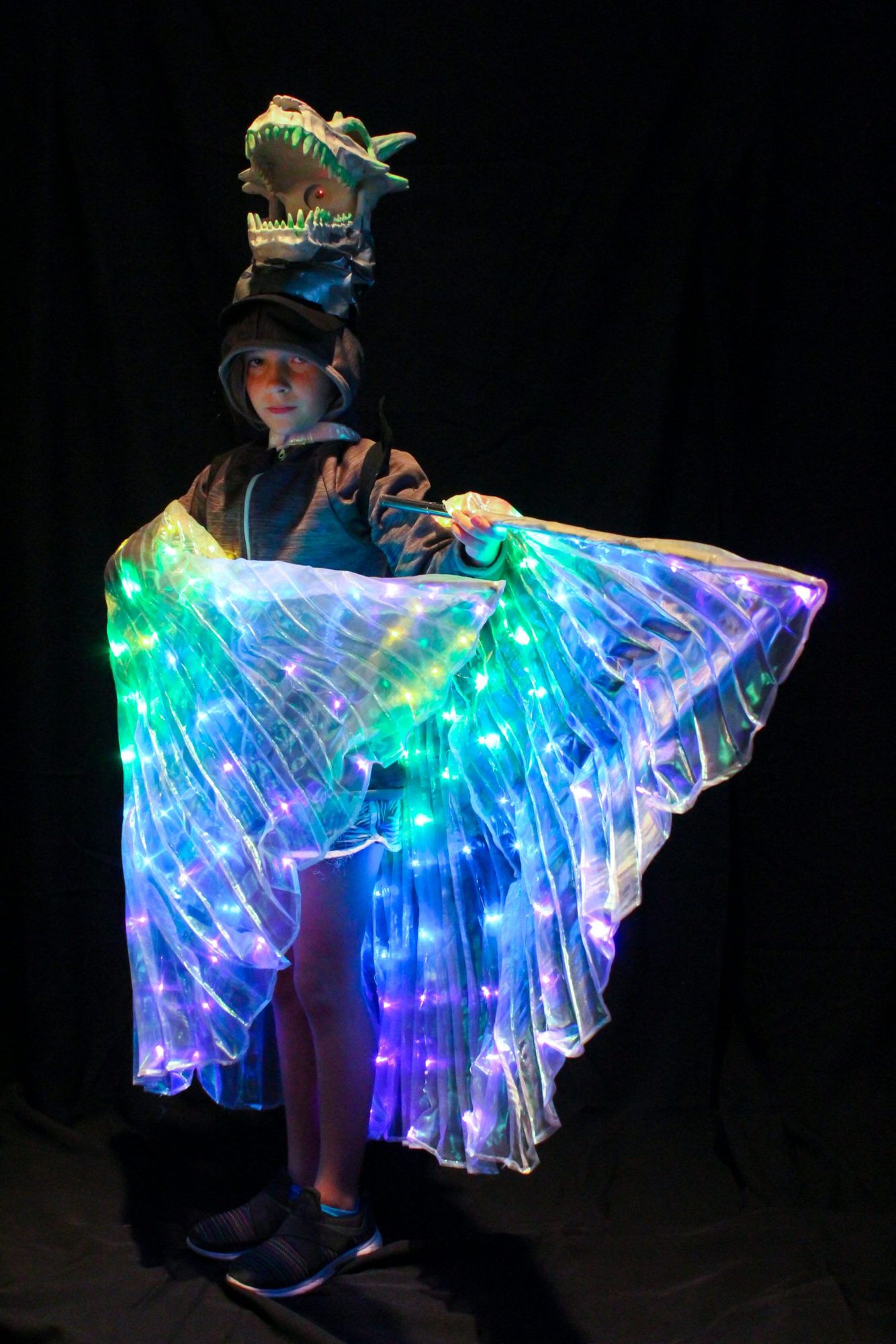 Student wearing illuminated dinosaur head and LED light-up wings