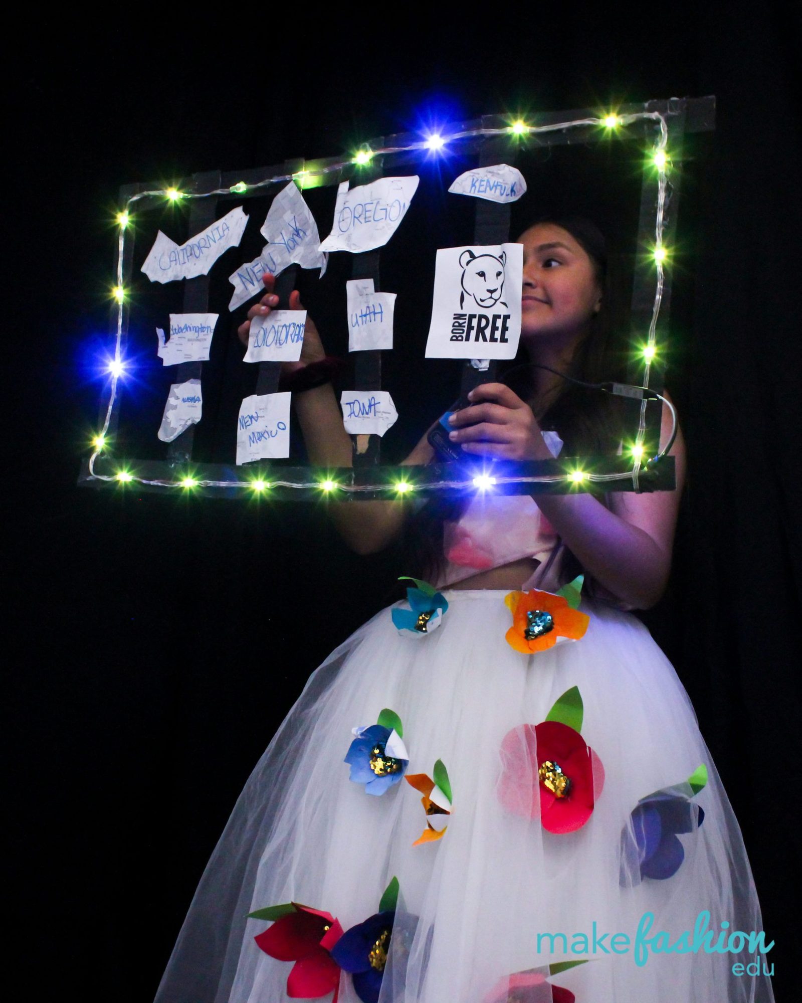 Student in a tulle skirt holding an LED-framed sign of state names