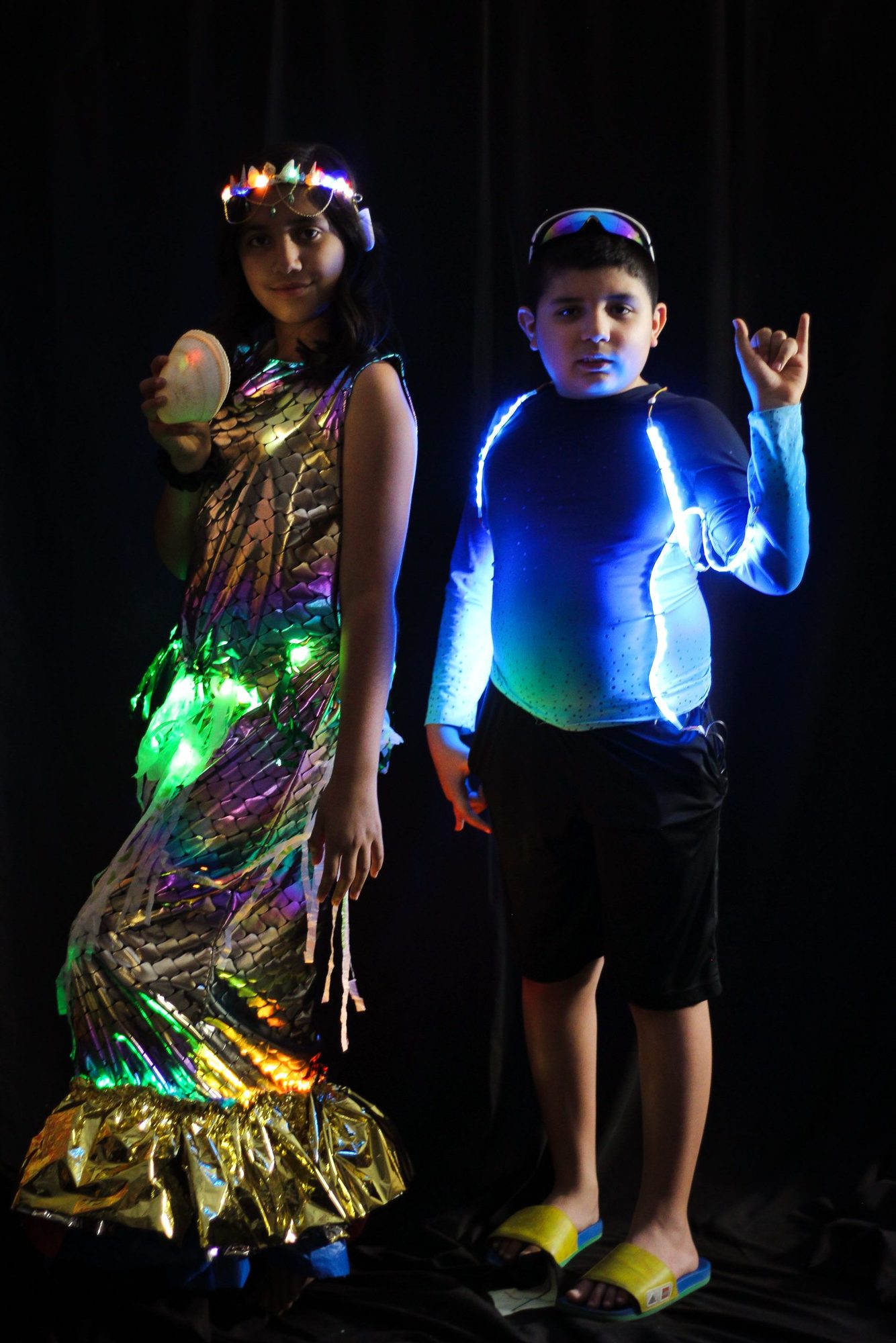 Two student models with illuminated garments featuring colorful and blue LED lights