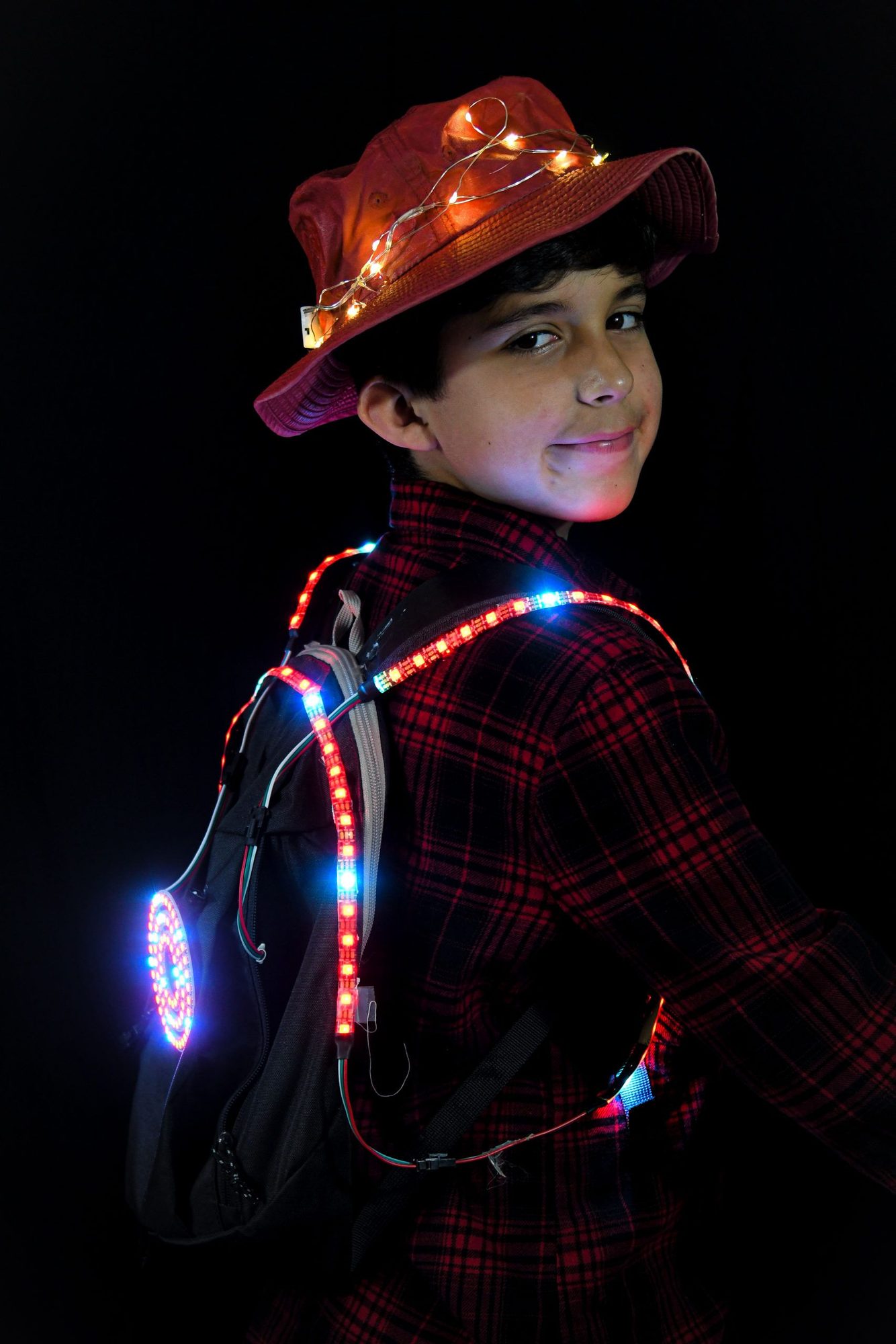 Student in red plaid outfit with warm LED lights and illuminated backpack