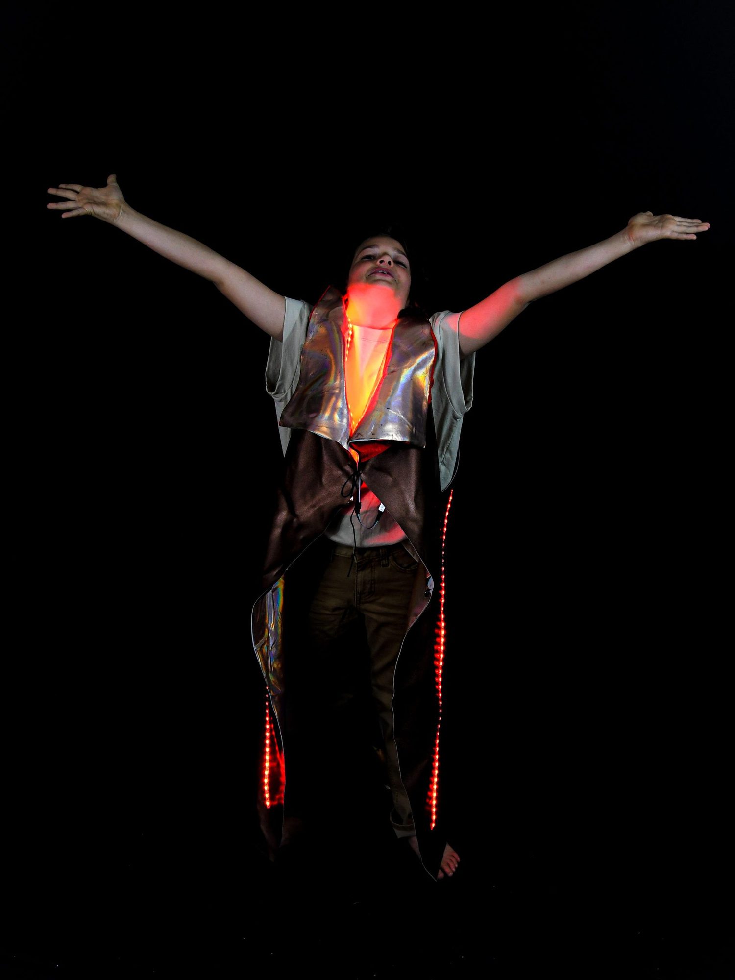 Student with arms raised wearing vest with glowing red and yellow LEDs