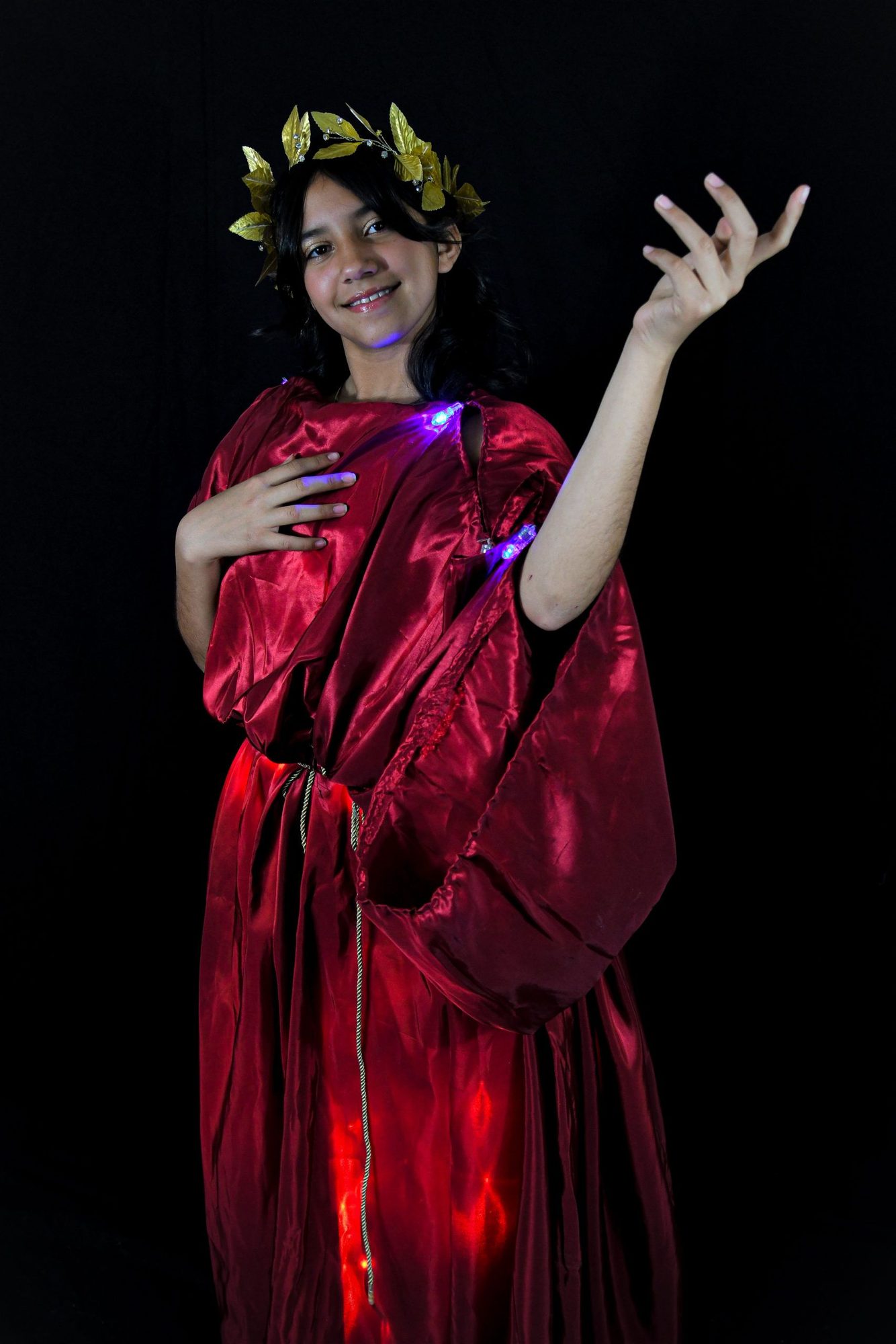 Student in red silk dress with golden leaf crown and glowing LED accents