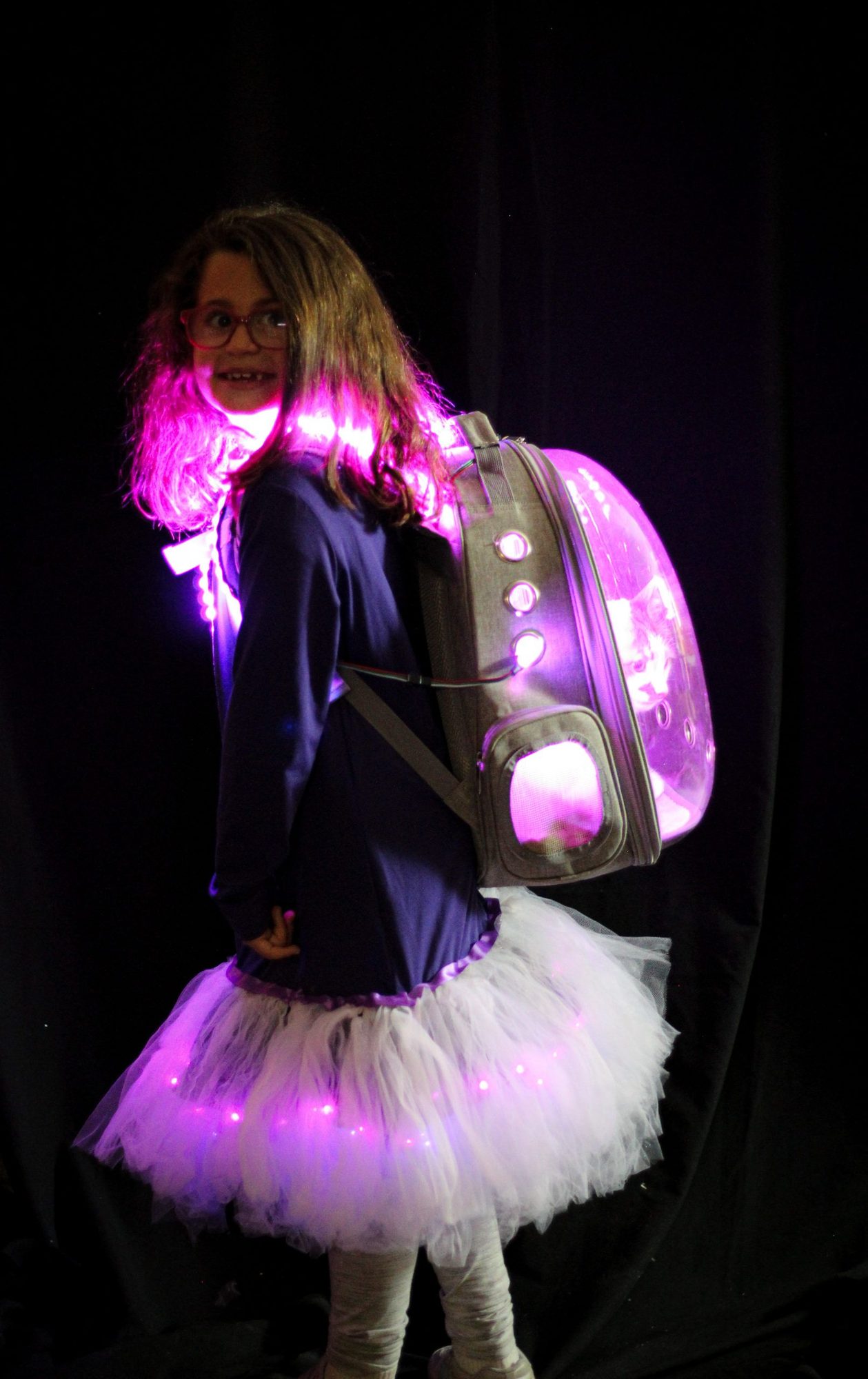 Student model in backpack and tulle skirt with glowing magenta LED lights