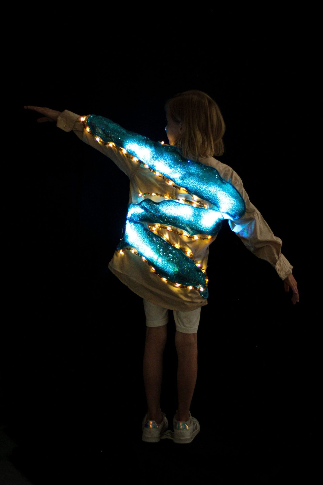 Student from behind wearing jacket with glowing blue and gold LED stripes