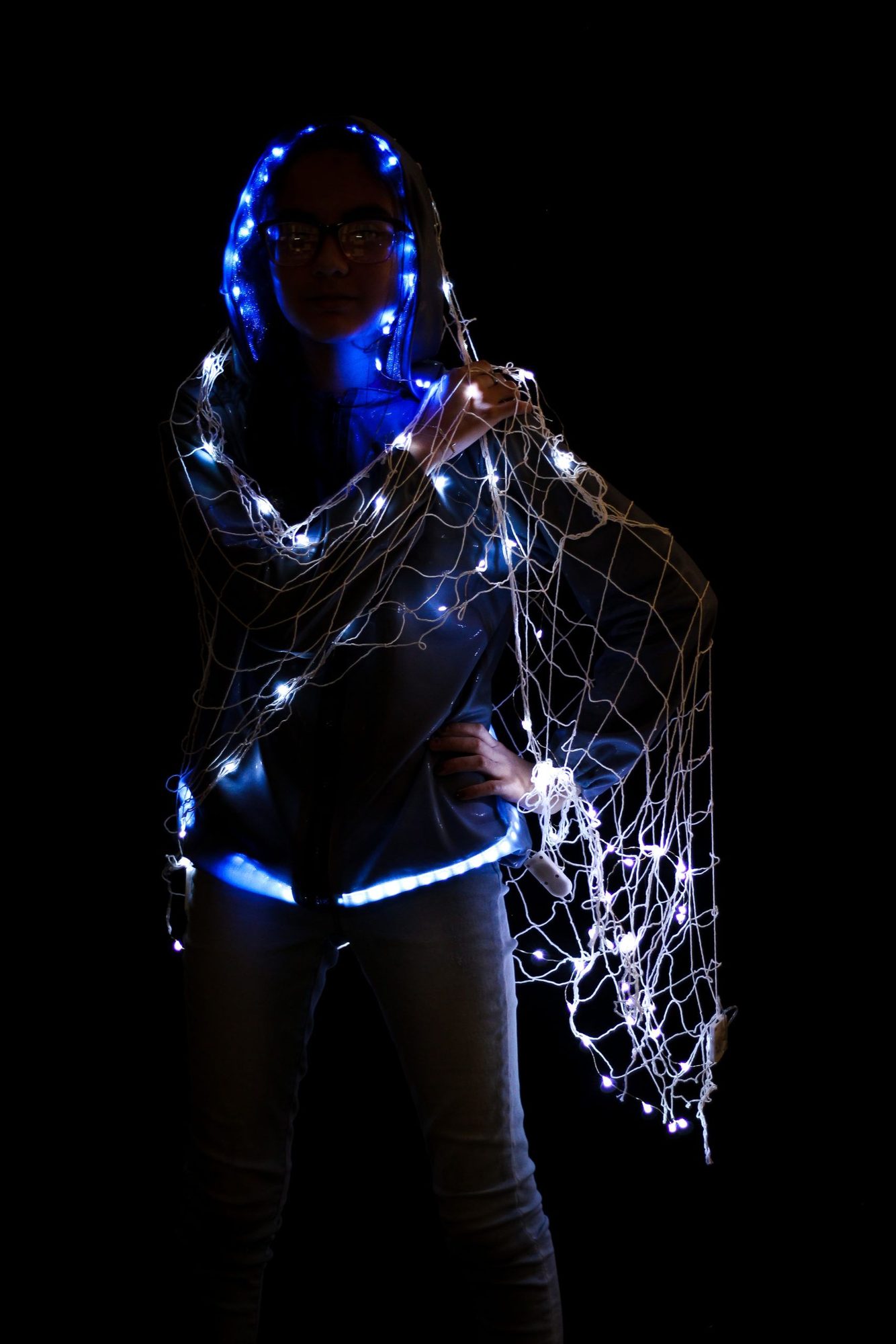 Student wearing light-up net cape with glowing blue and white LED lights